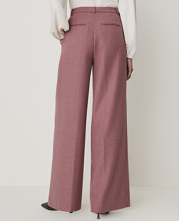 A person wearing wide-leg pink trousers stands against a plain white background.