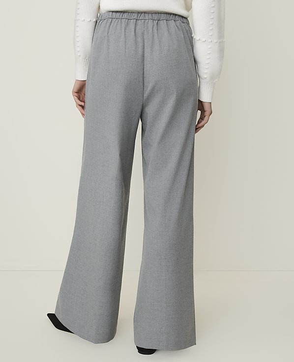 A person wearing wide-leg gray pants stands against a plain white background.