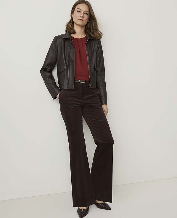 A woman in a brown leather jacket and corduroy pants stands against a plain white background.