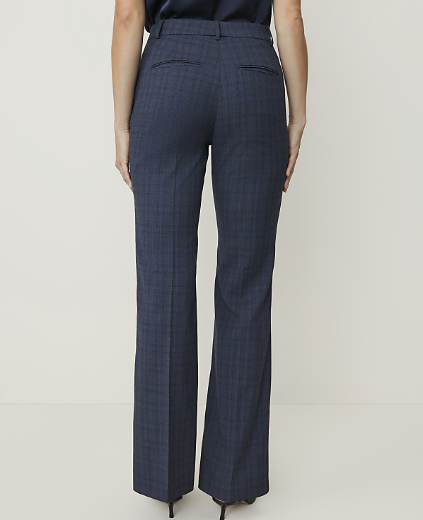 A person wearing navy plaid dress pants stands against a plain, light-colored background.