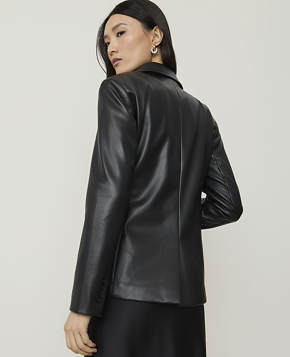 A woman in a black leather blazer is shown from the back against a plain, light-colored background.