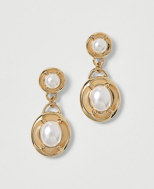 Gold dangle earrings with pearl accents hang against a plain white background.