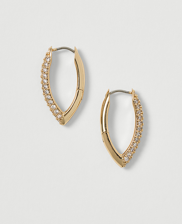 A pair of gold hoop earrings, encrusted with small diamonds, rest on a plain, light-colored background.