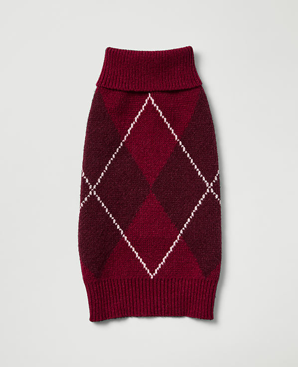 A burgundy argyle dog sweater with a ribbed collar and hem lies flat against a plain, light gray background.