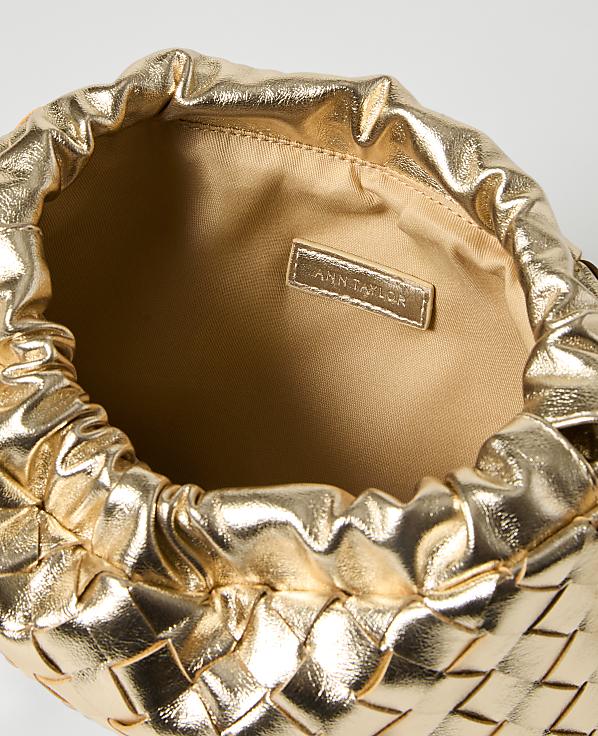 A metallic gold woven clutch with a cinched opening is presented against a plain white background.