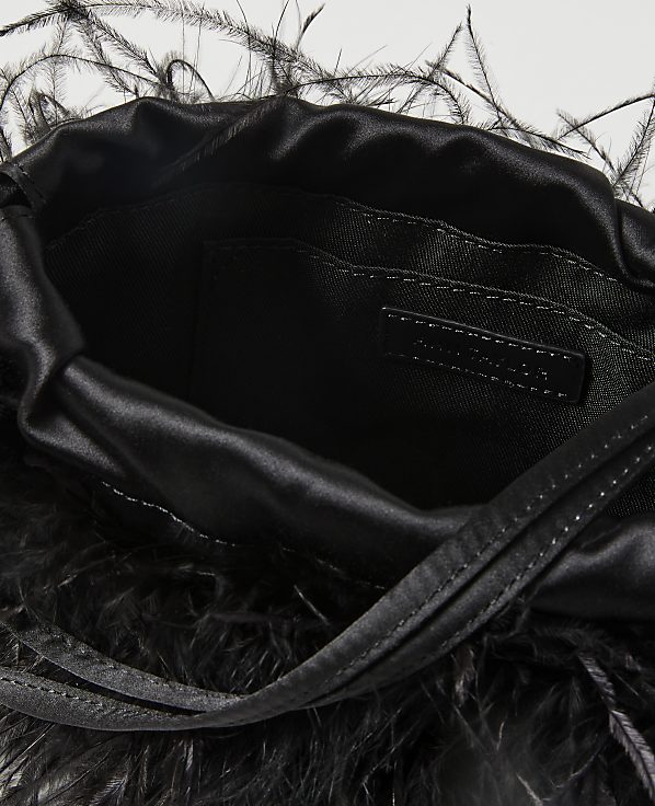 A black satin drawstring pouch bag adorned with black feathers in the foreground is set against a plain white background.