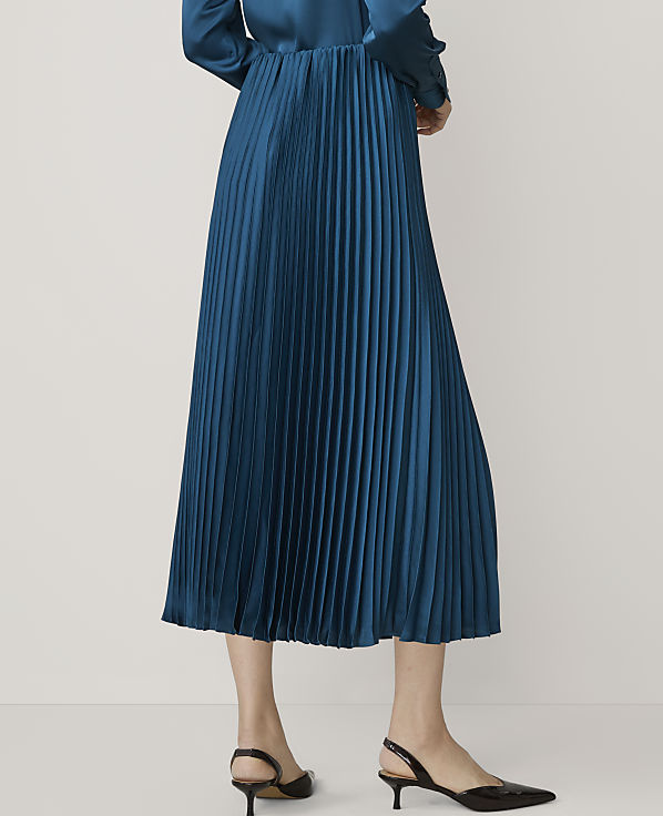 A teal pleated skirt with black slingback heels is shown against a plain white background.