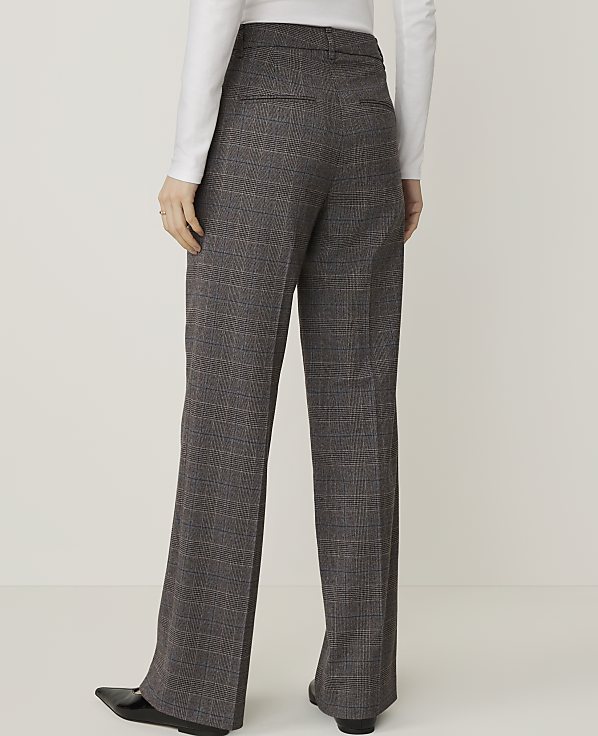 A person wearing plaid trousers stands against a plain white background.
