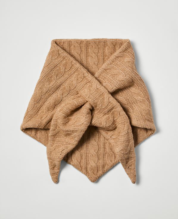 A tan cable-knit scarf is folded into a triangle and tied in the foreground against a plain white background.