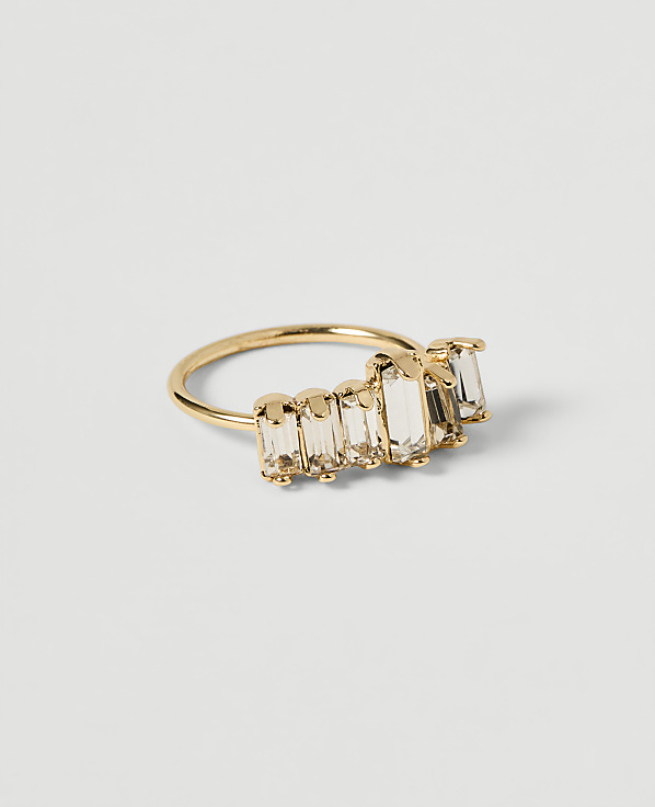 A gold ring with baguette-cut clear stones is displayed on a plain white background.