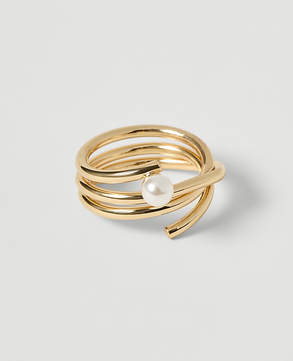 A coiled gold ring with a pearl accent rests on a plain white background.