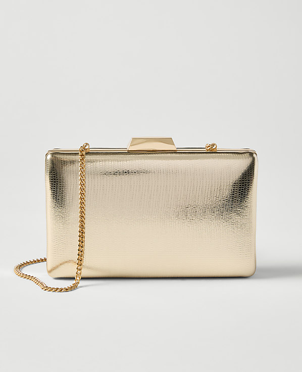 A textured gold clutch with a delicate gold chain rests on a plain white background.