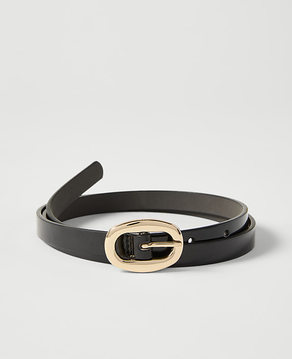 A black leather belt with a gold oval buckle lies on a plain white background.