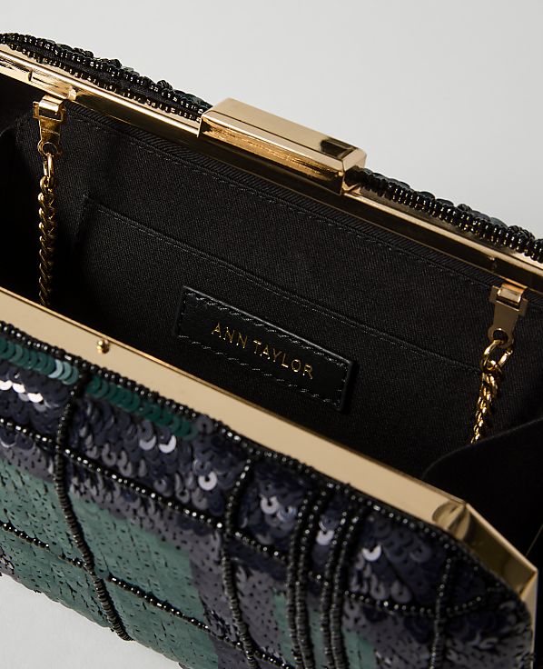 A close-up of an open, sequined clutch purse with a gold clasp and chain, set against a plain white background.