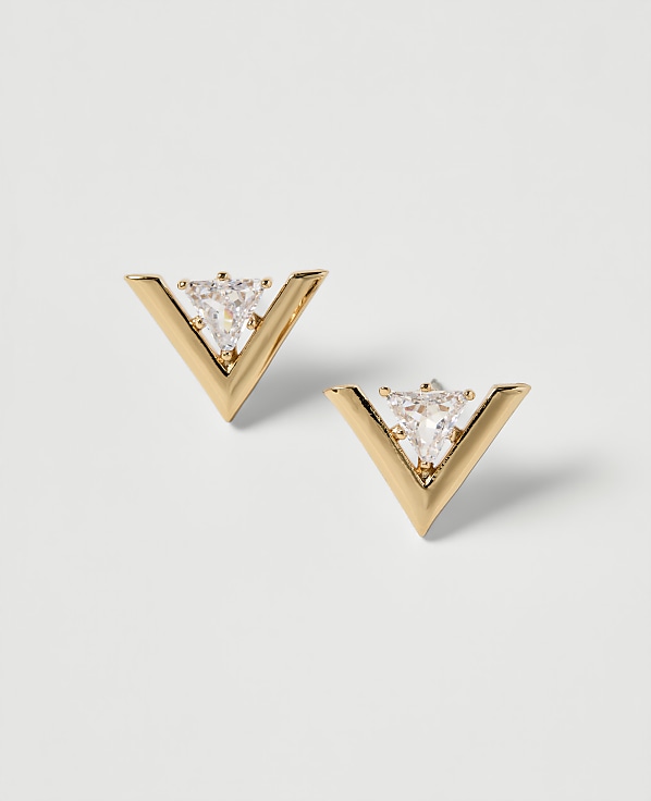 A pair of gold V-shaped earrings with clear triangular gemstones are displayed against a plain white background.