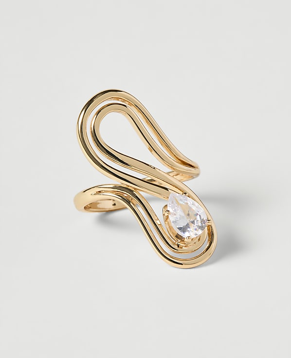 A gold ring with a pear-shaped diamond sits on a plain white background.