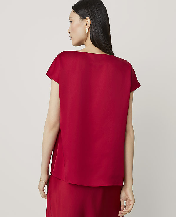 A woman in a red top and skirt stands against a plain background.