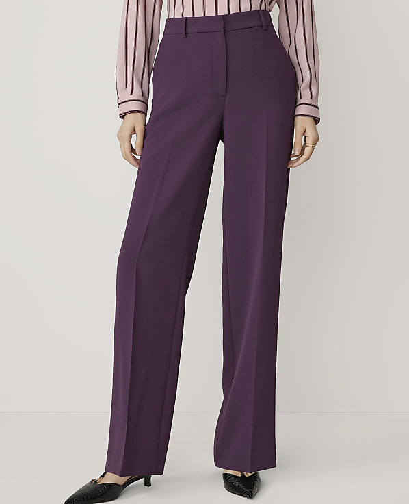 A person in purple wide-leg trousers and a striped top stands against a plain white background.