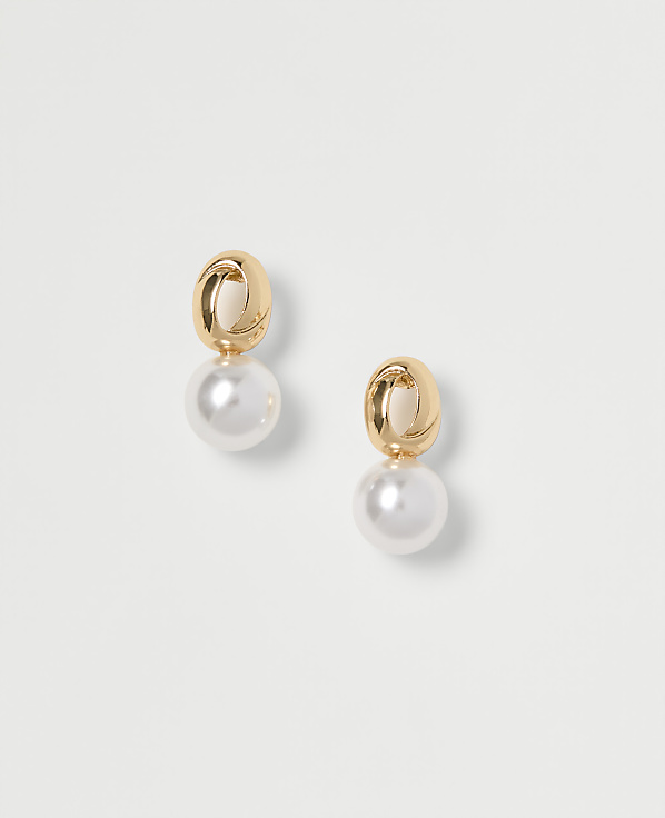 A pair of gold and pearl drop earrings are displayed against a plain white background.