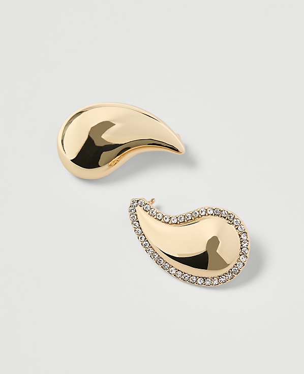 Two gold paisley-shaped earrings, one plain and the other encrusted with small diamonds, rest on a plain white background.
