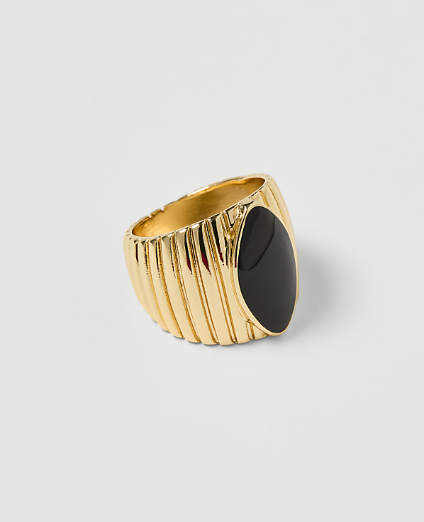 A gold ring with a ribbed band and an oval black stone sits on a plain white background.