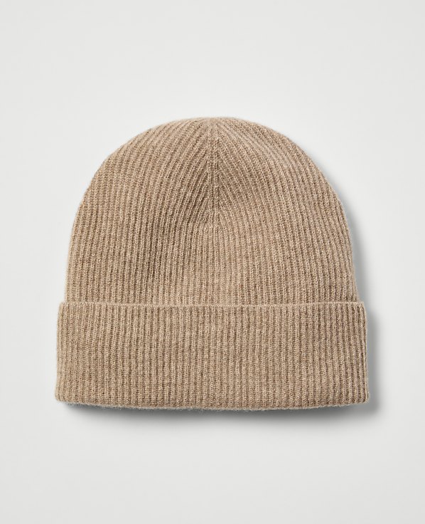 A ribbed, tan beanie with a folded brim rests on a plain, light gray background.