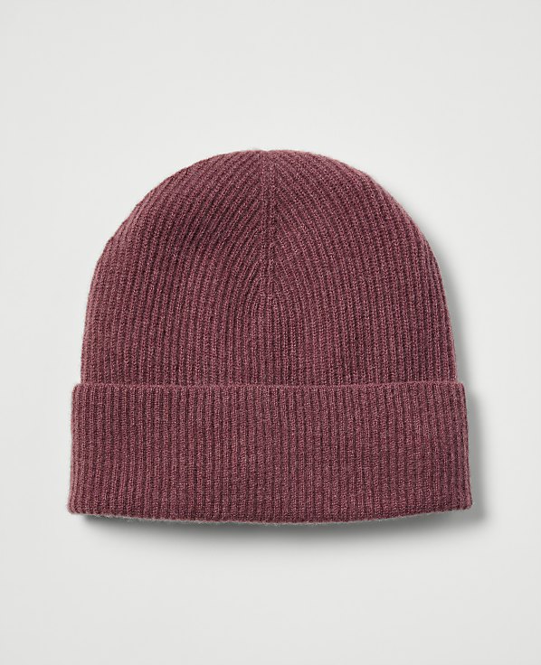 A maroon ribbed beanie with a folded brim rests against a plain, light gray background.