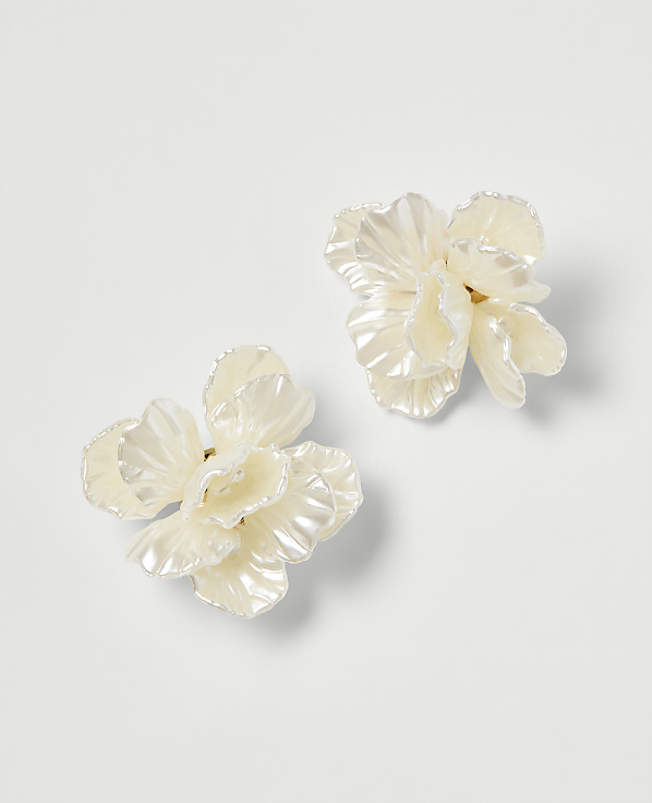Two delicate, pearl-white floral earrings rest on a plain white background.