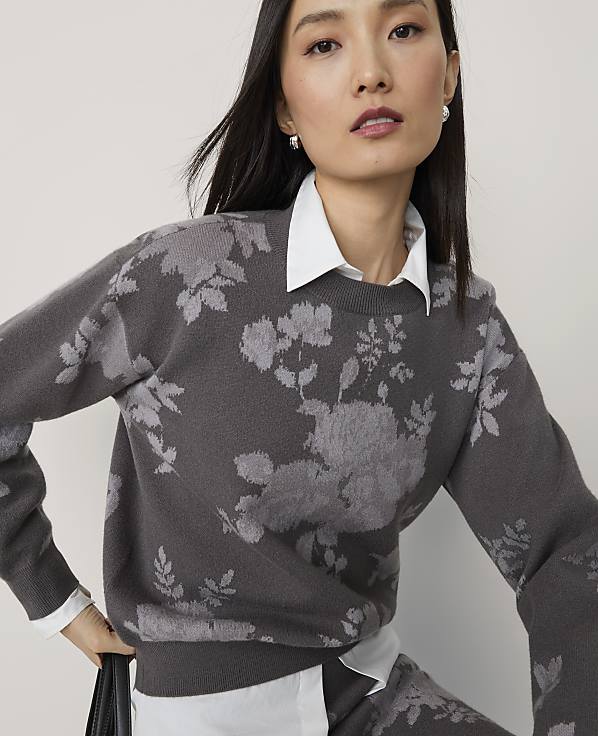 A woman in a floral sweater and white shirt is shown against a plain background.