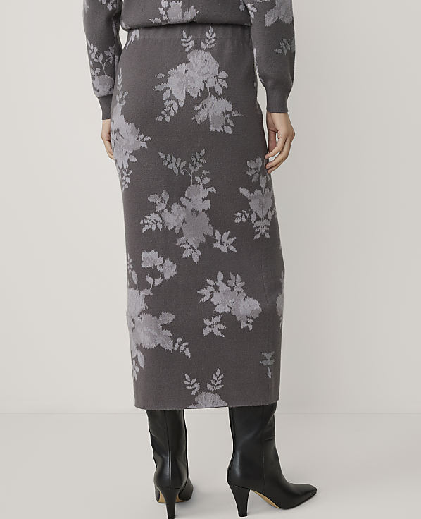 A person wearing a floral print skirt and black boots stands against a plain background.