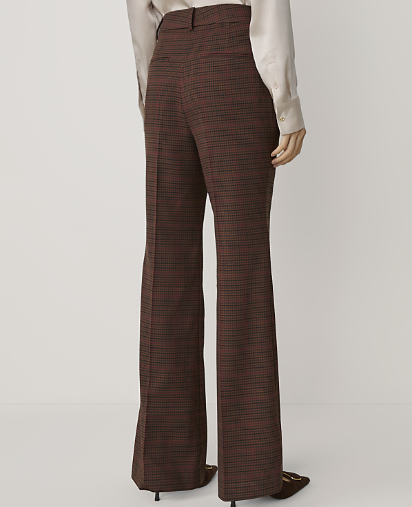 A person in flared, plaid trousers stands against a plain, light background.