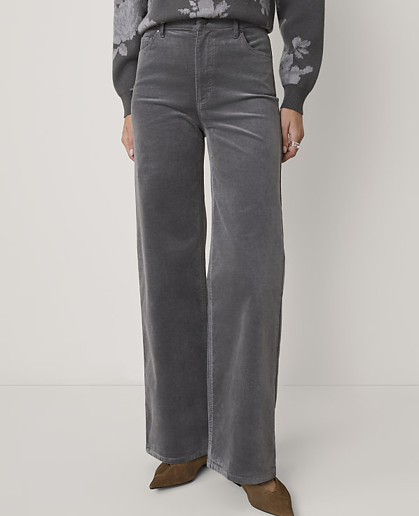 A person stands in gray corduroy wide-leg pants and a floral sweater against a plain gray background.