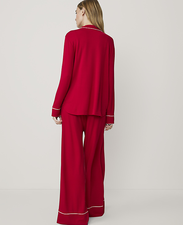 A woman in red pajamas stands against a plain white background.