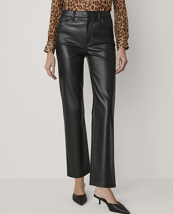 A person wearing black faux leather pants and a leopard print blouse stands against a plain white background.