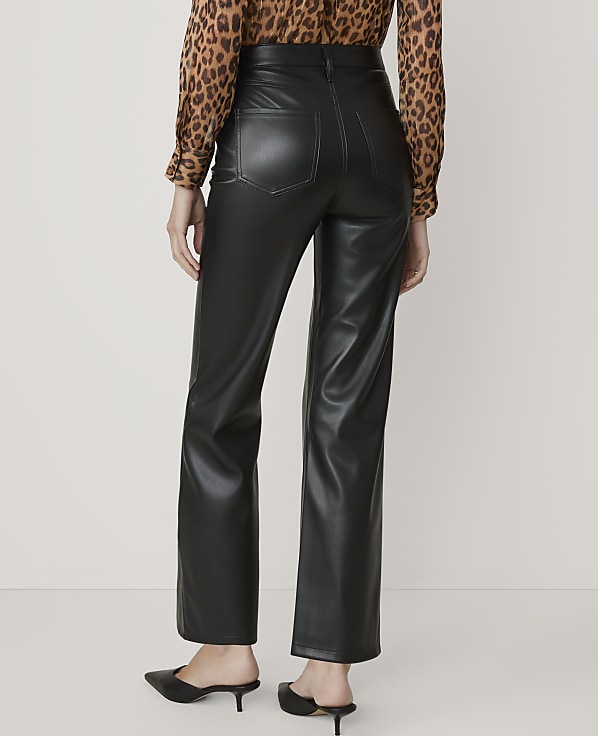 A person wearing black faux leather pants and a leopard print blouse stands against a plain, light-colored background.