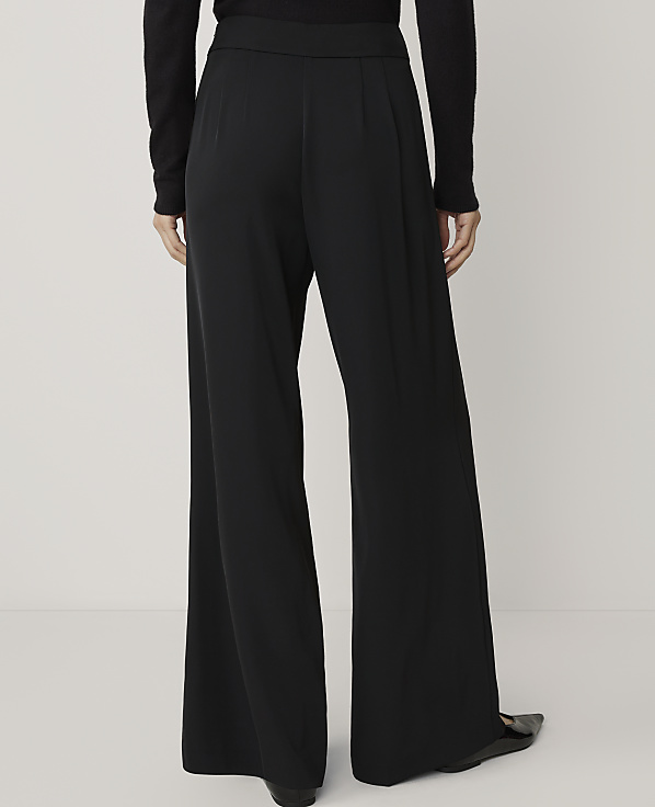 A person wearing black wide-leg pants stands against a plain white background.
