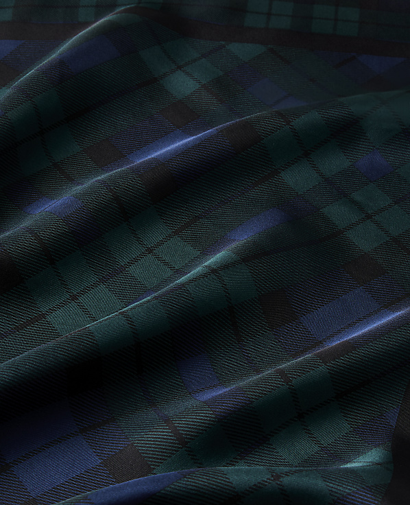 Draped folds of dark green and blue plaid fabric create a textured landscape of light and shadow.