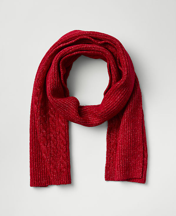 A shimmering red cable-knit scarf is looped in the center against a plain light gray background.