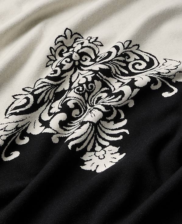 A black and white ornate damask pattern is woven into a draped fabric.