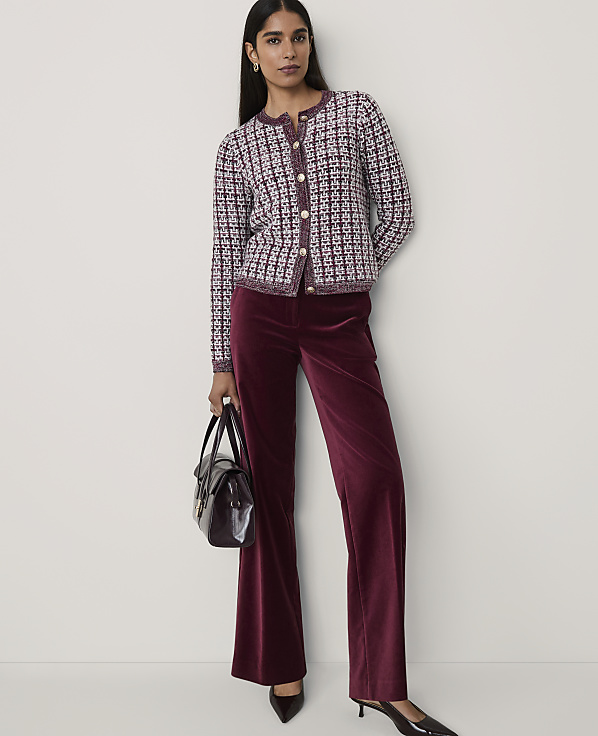 A woman wearing a purple tweed jacket and burgundy velvet trousers stands against a plain white background.