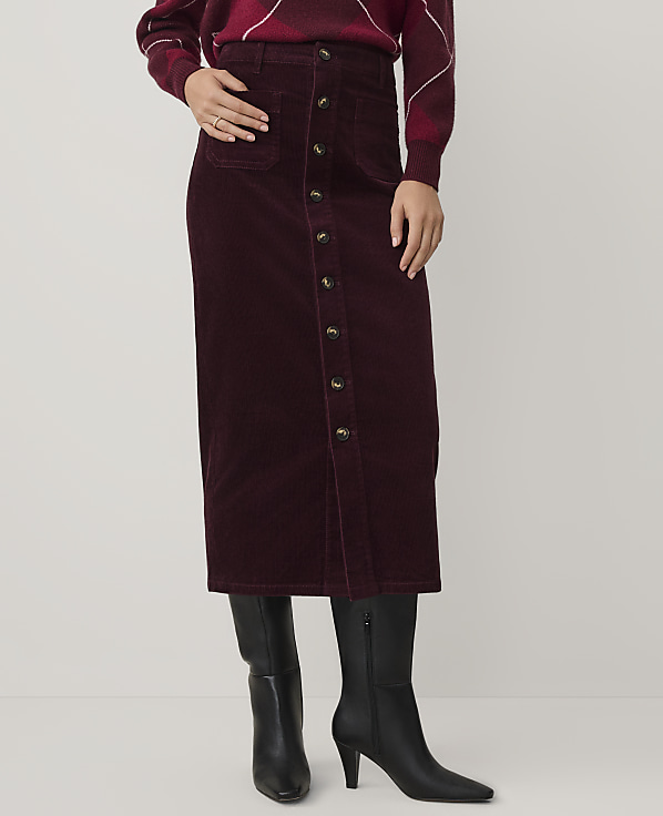 A person wears a burgundy corduroy button-down skirt and black boots against a plain white background.