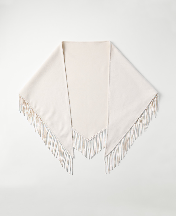 A cream-colored fringed shawl is laid flat against a plain white background.