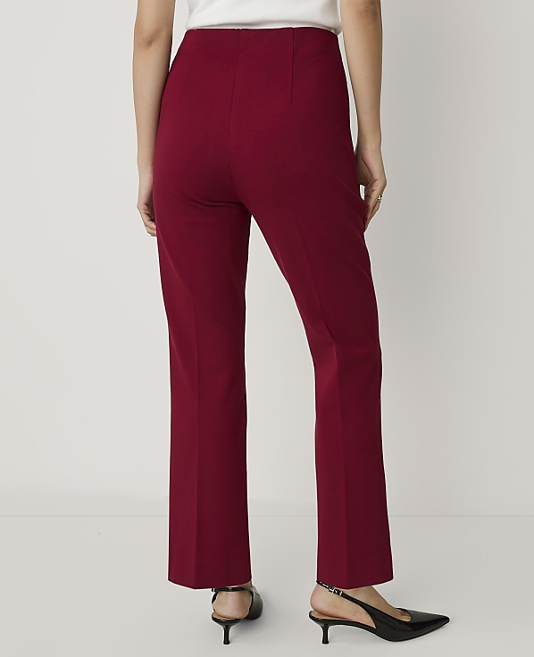 A person wearing red trousers and black heels stands against a plain white background.