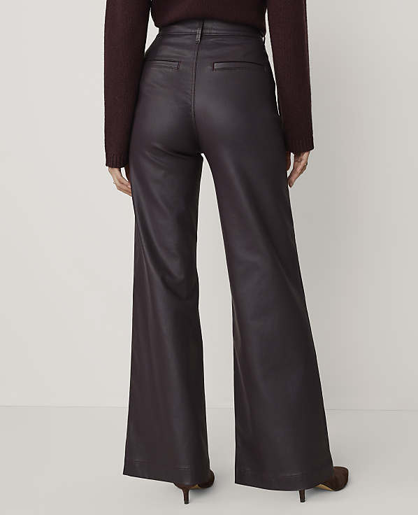 A person wearing a dark purple sweater and wide-leg faux leather trousers stands against a plain, light-colored background.