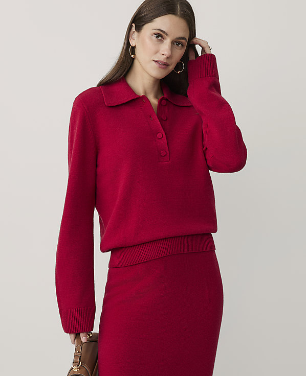 A woman wearing a red knit sweater and matching skirt stands against a plain, light-colored background.