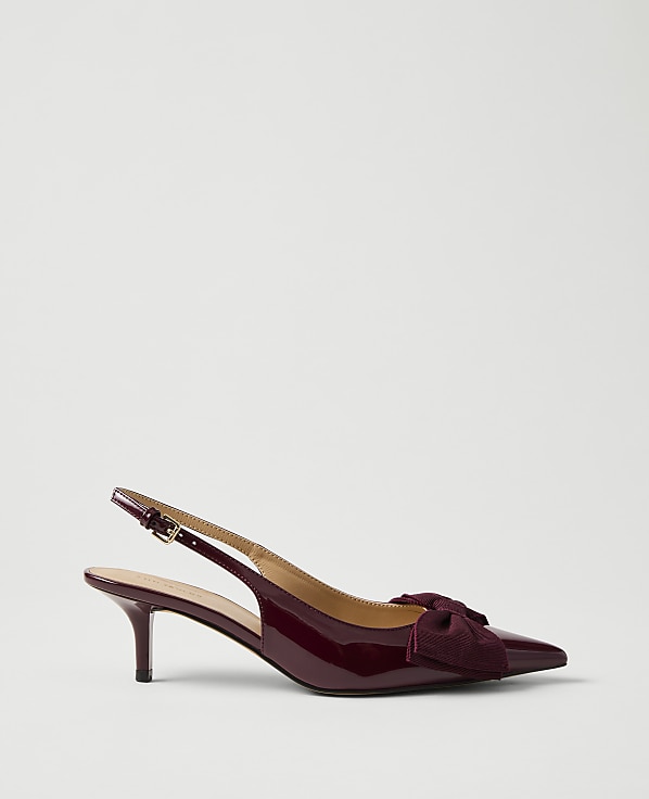 A single burgundy patent leather slingback heel with a bow sits against a plain, light grey background.