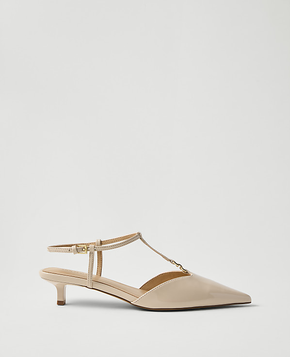 A single beige patent leather kitten heel with an ankle strap sits against a plain, light grey background.