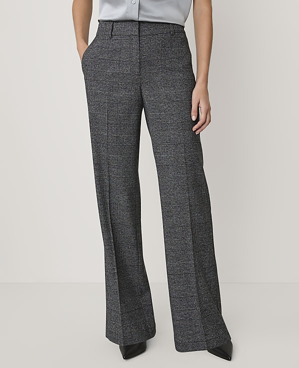 A person wears grey patterned wide-leg trousers and a light blue shirt against a plain white background.