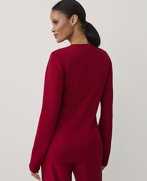 A woman wearing a red long-sleeved top and matching pants stands against a plain, light-colored background.
