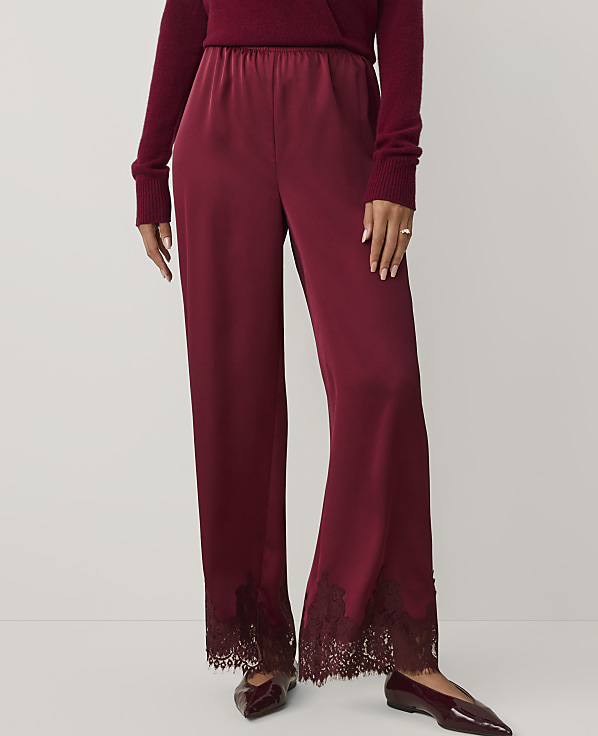 A person wears a burgundy sweater and matching satin trousers with lace hems against a plain white background.